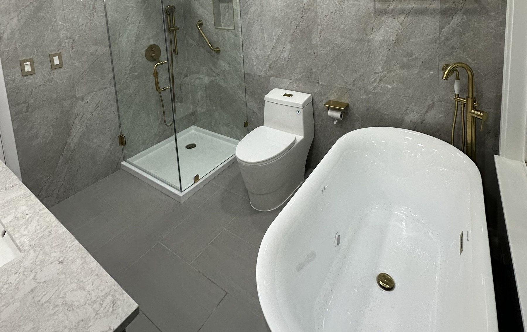Gray marble bathroom remodel with glass shower and freestanding tub